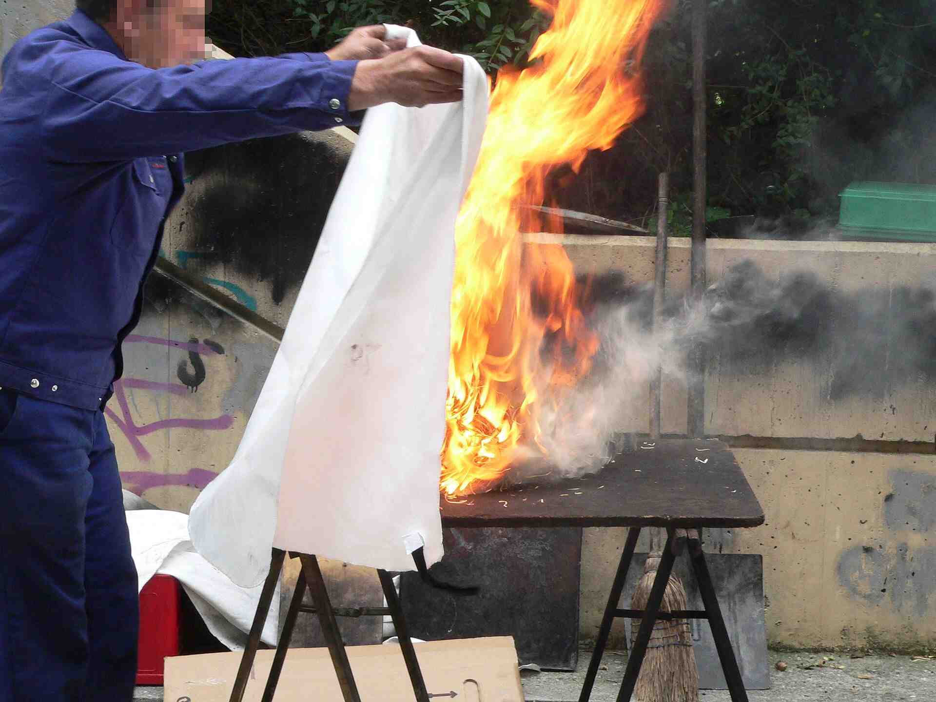 Person holding fire blanket ready to smother a fire.