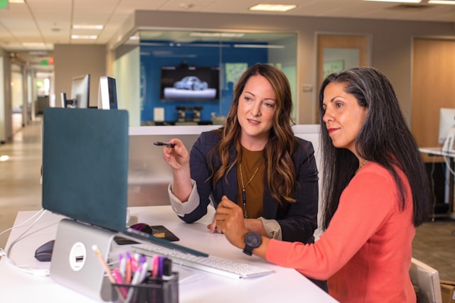 Two women sitting in an office workplace discussing evacuation plan.